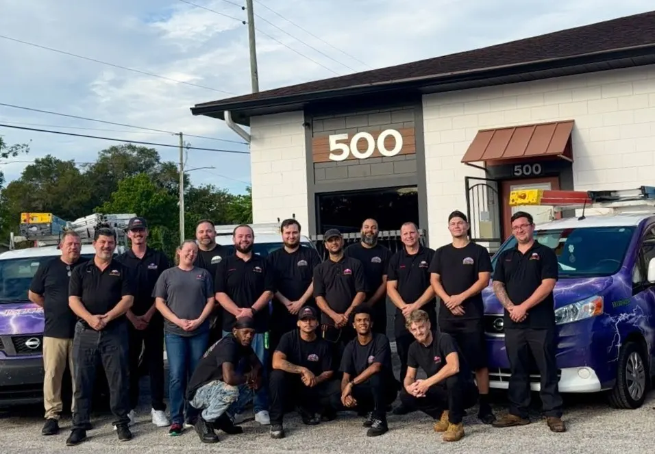 The In Phaze Electric team in front of the shop with two purple company vans